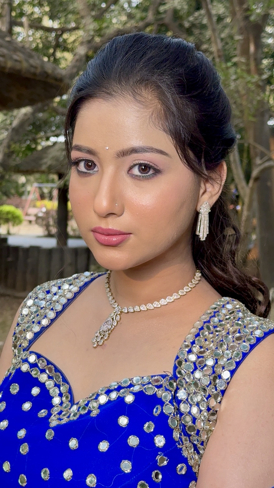 Guest glam makeup with a blue embellished blouse