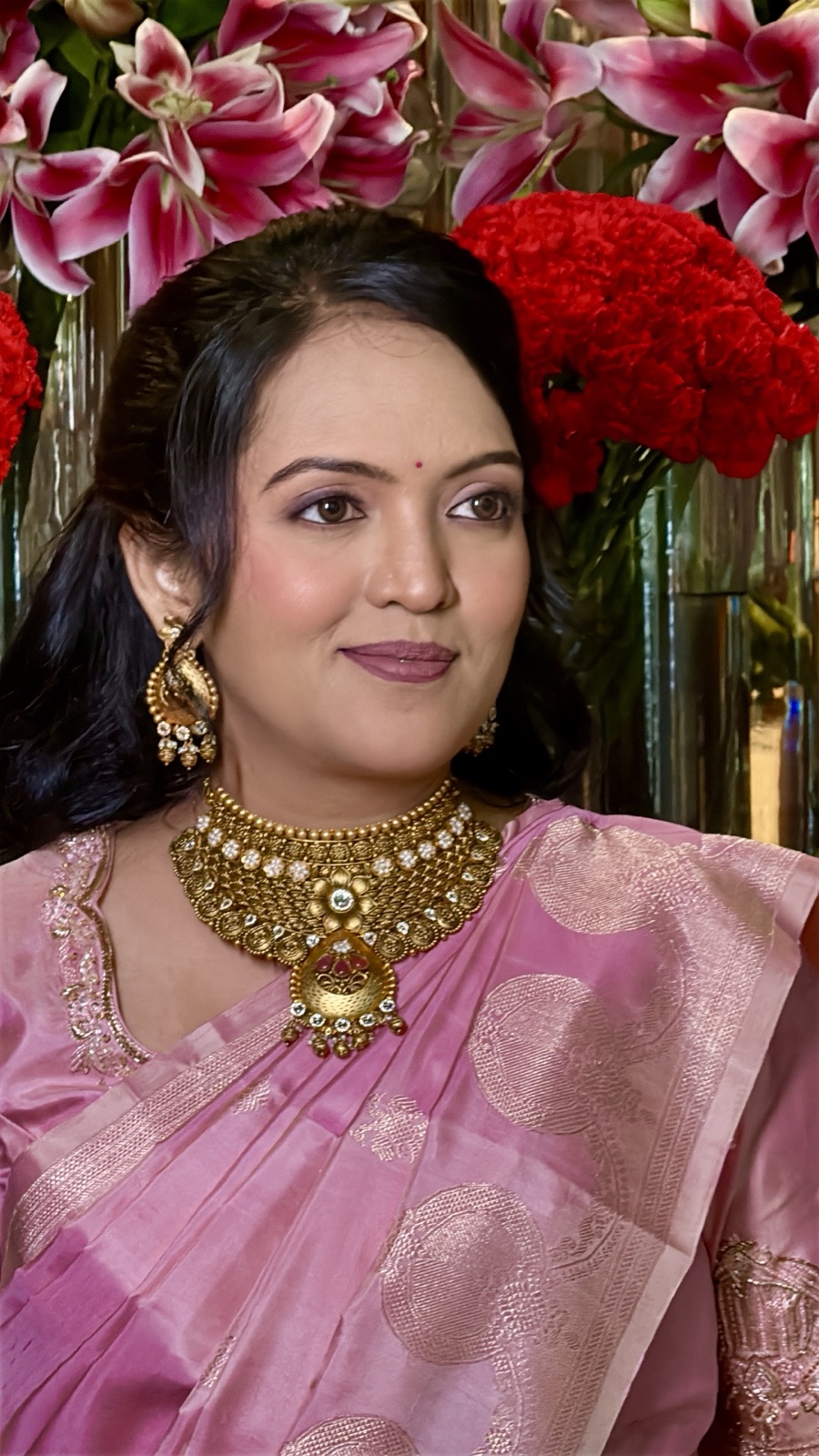 Soft glam guest look in pink against a floral backdrop